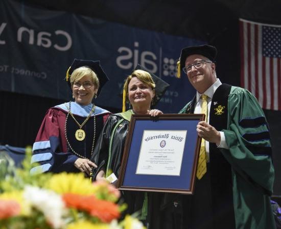 Professor of 职业治疗 Mary Siniscaro stands between Provost Todd Pfannestiel and President Laura Casamento, holding her award at the 2023 Undergraduate Commencement Ceremony.